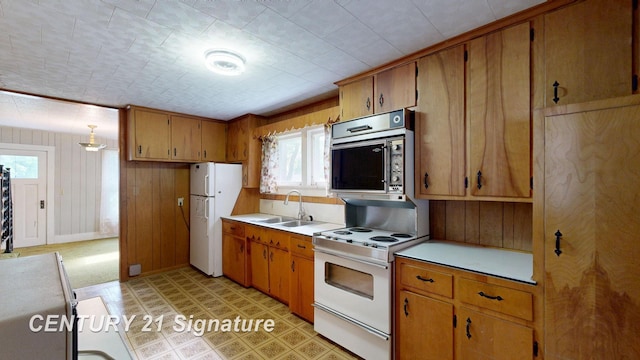 107 E Johns St, Durand, MI 48429 - kitchen with white appliances, a sink, light countertops, brown cabinets, and wood walls