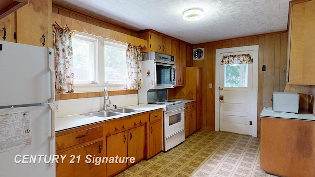 107 E Johns St, Durand, MI 48429 - kitchen with white appliances, a sink, light countertops, brown cabinetry, and wood walls