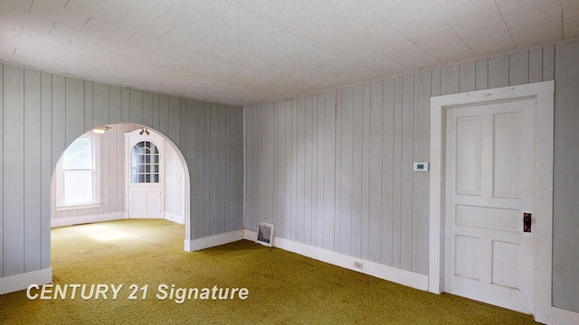 107 E Johns St, Durand, MI 48429 - carpeted empty room with arched walkways, baseboards, and wooden walls