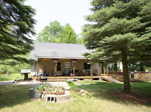 7484 Cedar Lake Rd, Oscoda, MI 48750 - rear view of house with a lawn, roof with shingles, and a wooden deck