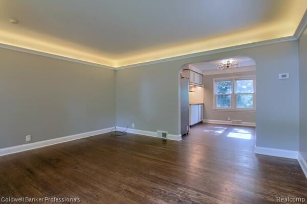 25811 Briarbank Ave, Southfield, MI 48033 - empty room with arched walkways, dark wood-type flooring, a chandelier, baseboards, and crown molding