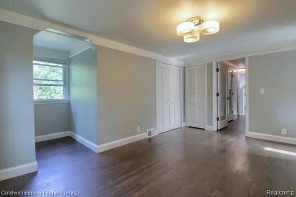 25811 Briarbank Ave, Southfield, MI 48033 - unfurnished room featuring arched walkways, wood finished floors, baseboards, and a chandelier