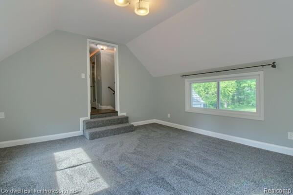 25811 Briarbank Ave, Southfield, MI 48033 - bonus room featuring lofted ceiling, dark carpet, baseboards, and stairway
