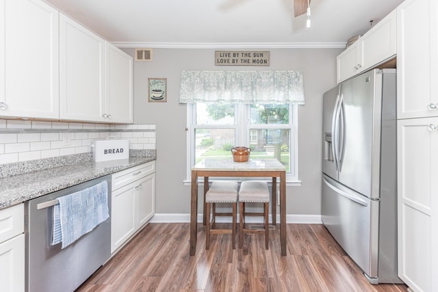386 Hartman Ln, Saline, MI 48176 - kitchen with appliances with stainless steel finishes, crown molding, tasteful backsplash, wood finished floors, and white cabinetry