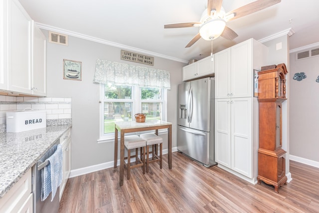 386 Hartman Ln, Saline, MI 48176 - kitchen featuring stainless steel appliances, crown molding, light wood-style floors, tasteful backsplash, and white cabinets