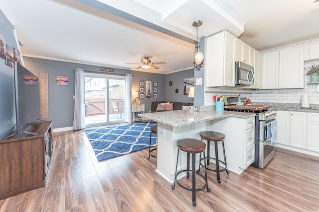 386 Hartman Ln, Saline, MI 48176 - kitchen featuring appliances with stainless steel finishes, ornamental molding, light wood-style flooring, decorative backsplash, and a kitchen breakfast bar