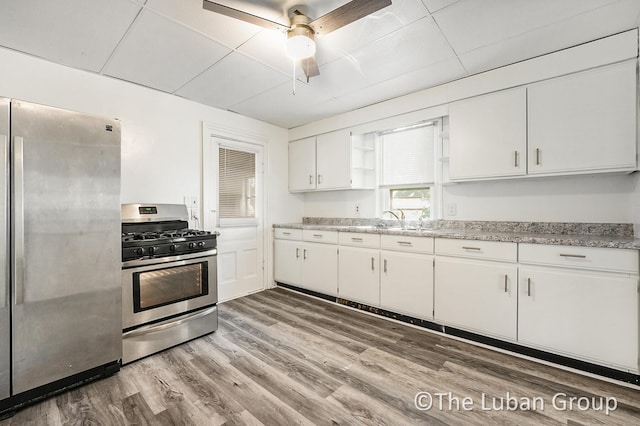 630 Prospect Ave NE, Grand Rapids, MI 49503 - kitchen with appliances with stainless steel finishes, a sink, white cabinetry, light wood finished floors, and ceiling fan