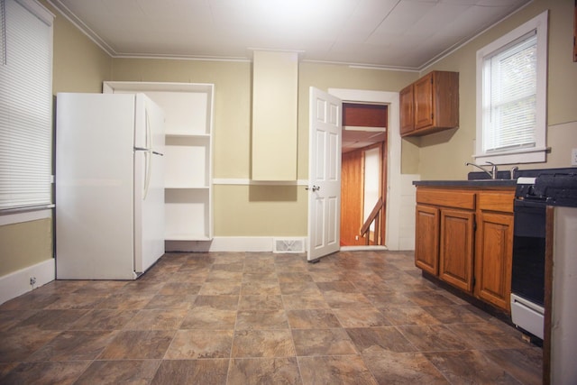 121 Houseman Ave NE, Grand Rapids, MI 49503 - kitchen featuring freestanding refrigerator, range with gas cooktop, dark countertops, brown cabinetry, and ornamental molding