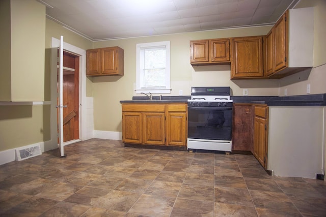 121 Houseman Ave NE, Grand Rapids, MI 49503 - kitchen featuring white gas range, dark countertops, brown cabinets, and a sink