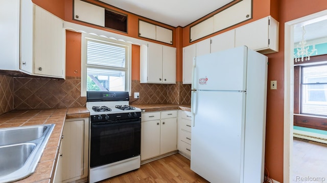218 Clifford St, Lansing, MI 48912 - kitchen with freestanding refrigerator, gas range oven, tile counters, white cabinets, and healthy amount of natural light