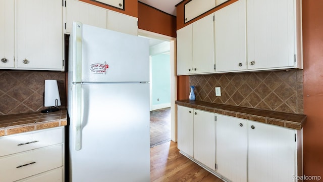218 Clifford St, Lansing, MI 48912 - kitchen with freestanding refrigerator, tasteful backsplash, light wood-style flooring, and white cabinetry