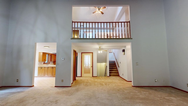 160 Wire Line Rd, Caro, MI 48723 - unfurnished living room with ceiling fan, carpet flooring, a high ceiling, baseboards, and stairs