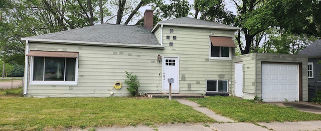 1781 Davis St, Muskegon, MI 49441 - back of house with a chimney, a yard, a shingled roof, and a garage