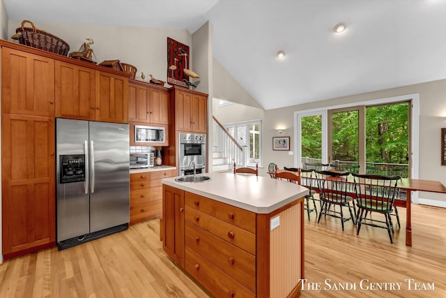 8985 Lakeshore Dr, West Olive, MI 49460 - kitchen featuring stainless steel fridge, light wood-type flooring, light countertops, built in microwave, and an island with sink