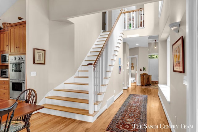 8985 Lakeshore Dr, West Olive, MI 49460 - stairs featuring wood finished floors, a high ceiling, and baseboards