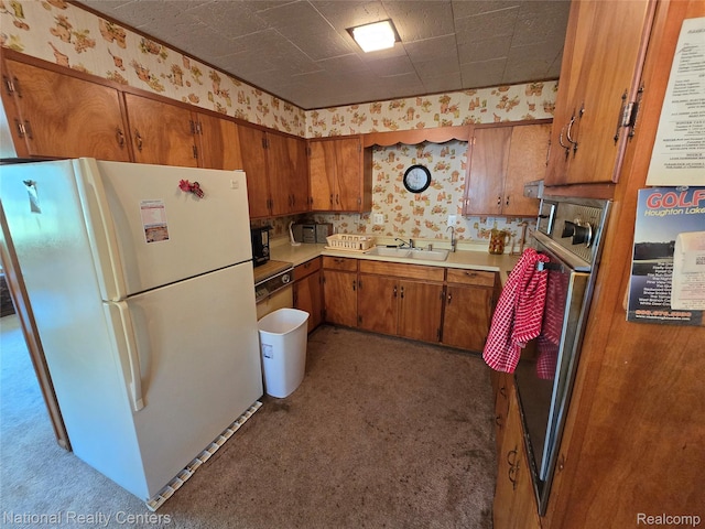 10475 W Higgins Lake Dr, Roscommon, MI 48653 - kitchen featuring freestanding refrigerator, wallpapered walls, brown cabinetry, light countertops, and carpet floors