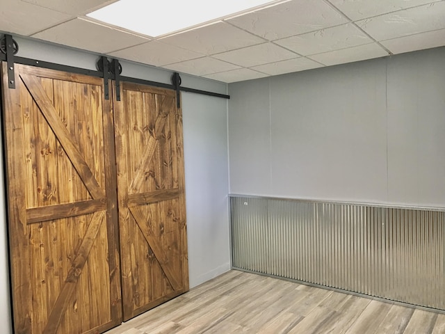 66223 Grey Lake Rd, Sturgis, MI 49091 - unfurnished room featuring a barn door, a paneled ceiling, and wood finished floors
