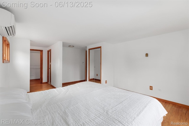 8173 Earhart Rd, South Lyon, MI 48178 - bedroom featuring a wall mounted AC, light wood-style flooring, and baseboards