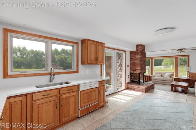 8173 Earhart Rd, South Lyon, MI 48178 - kitchen featuring dishwashing machine, a sink, light countertops, a wood stove, and light tile patterned floors