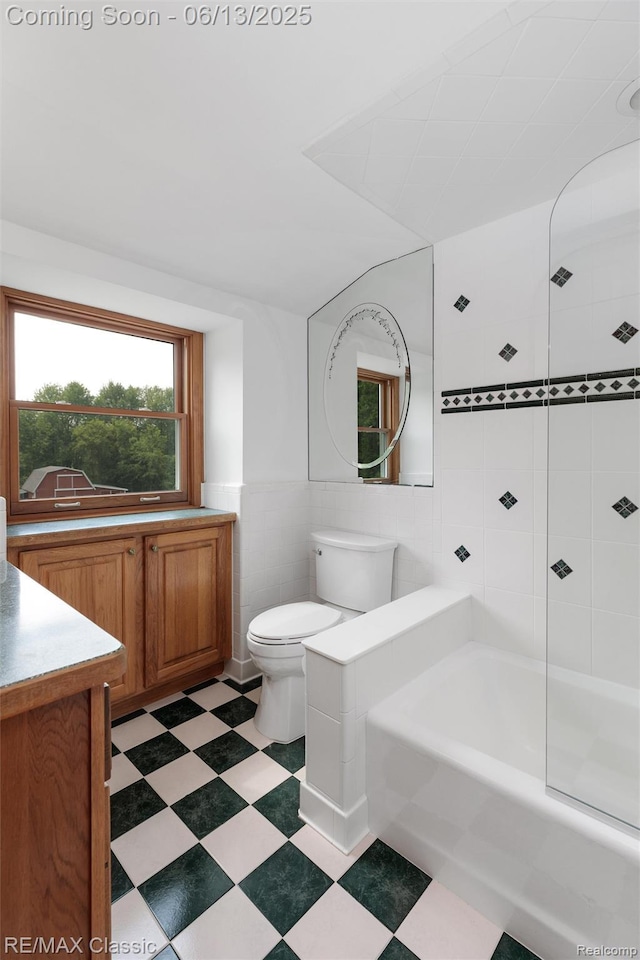 8173 Earhart Rd, South Lyon, MI 48178 - bathroom with tile walls, vanity, toilet, tub / shower combination, and tile patterned floors