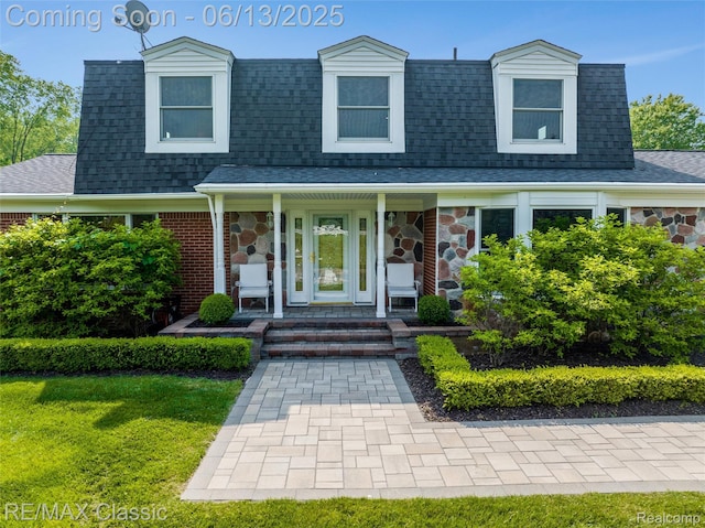 8173 Earhart Rd, South Lyon, MI 48178 - view of front of property featuring a shingled roof, covered porch, stone siding, and a front lawn