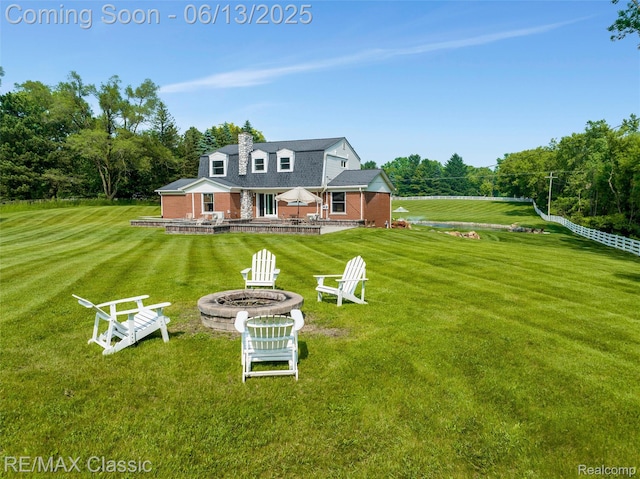 8173 Earhart Rd, South Lyon, MI 48178 - back of house with an outdoor fire pit, a lawn, a chimney, and brick siding