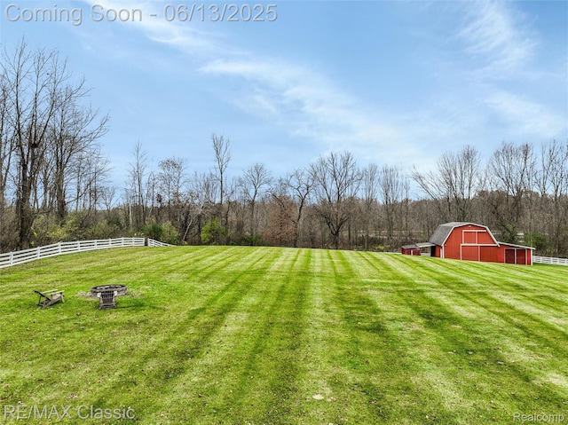 8173 Earhart Rd, South Lyon, MI 48178 - view of yard featuring a barn, an outbuilding, a wooded view, a fire pit, and a rural view