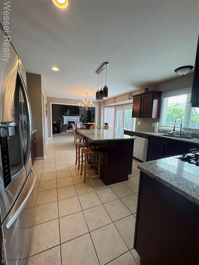 14232 Berryknoll Dr, Shelby Twp, MI 48315 - kitchen with stainless steel appliances, a sink, stone countertops, light tile patterned floors, and a kitchen island