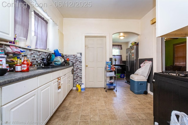 319 Marlborough St, Detroit, MI 48215 - kitchen with arched walkways, stainless steel refrigerator with ice dispenser, dark countertops, white cabinets, and a sink
