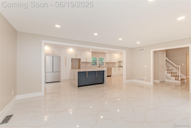 21993 Riverview Dr, Bloomfield Hills, MI 48025 - kitchen featuring stainless steel appliances, white cabinets, light marble finish flooring, recessed lighting, and light countertops