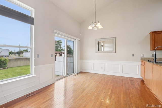 3871 Elvera Ln, Warren, MI 48092 - unfurnished dining area featuring a chandelier, light wood-style floors, wainscoting, and high vaulted ceiling