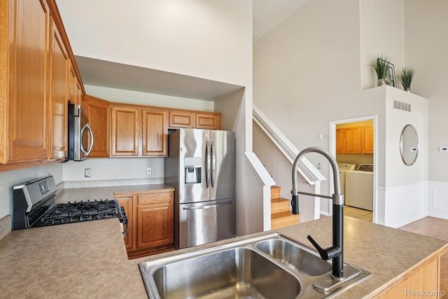 3871 Elvera Ln, Warren, MI 48092 - kitchen featuring stainless steel appliances, washer and clothes dryer, high vaulted ceiling, brown cabinets, and light countertops
