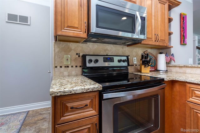 6081 Byram Lake Dr, Linden, MI 48451 - kitchen featuring appliances with stainless steel finishes, brown cabinetry, tasteful backsplash, and light stone counters