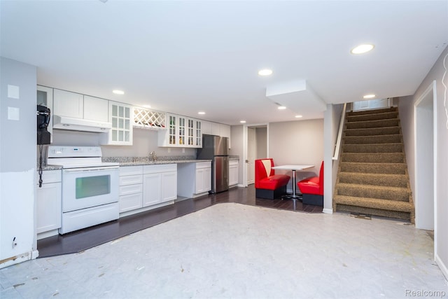 6081 Byram Lake Dr, Linden, MI 48451 - kitchen with white range with electric cooktop, freestanding refrigerator, under cabinet range hood, white cabinets, and glass insert cabinets