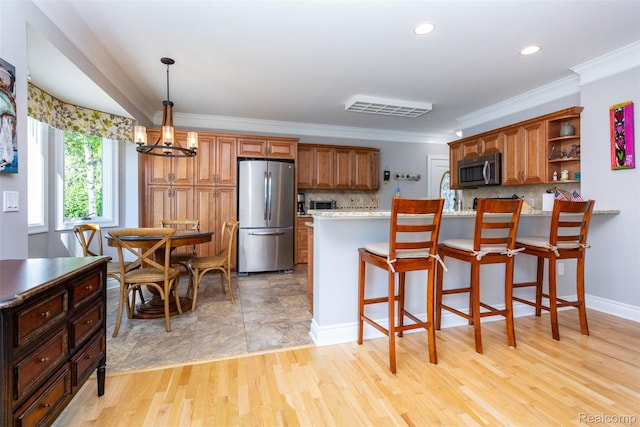 6081 Byram Lake Dr, Linden, MI 48451 - kitchen featuring stainless steel appliances, brown cabinetry, backsplash, a chandelier, and ornamental molding