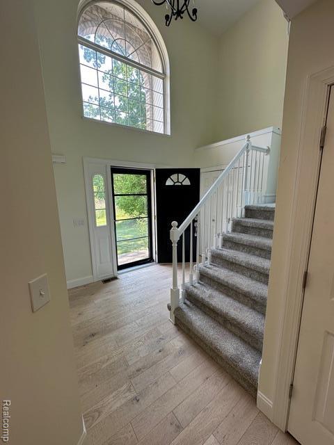 1727 Pero Lake Rd, Lapeer, MI 48446 - foyer featuring hardwood / wood-style floors, a high ceiling, stairway, baseboards, and a chandelier