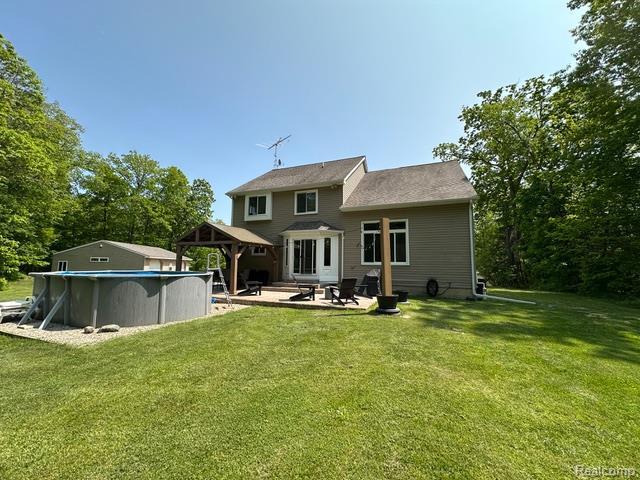 1727 Pero Lake Rd, Lapeer, MI 48446 - rear view of property featuring a gazebo, a lawn, an outdoor pool, and a patio area