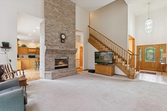 3438 Sandy Shore Dr, Metamora, MI 48455 - living room featuring a towering ceiling, stairway, carpet, and a brick fireplace