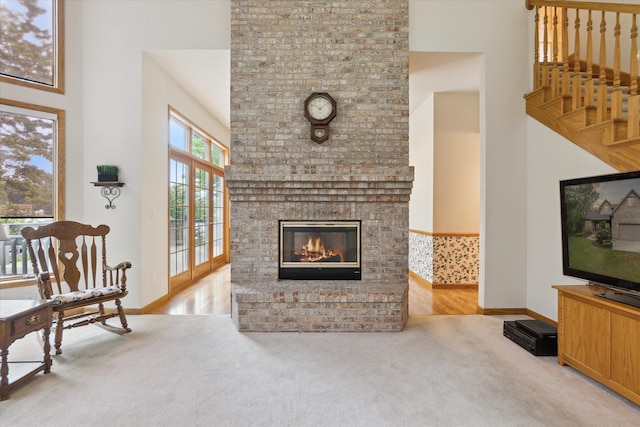 3438 Sandy Shore Dr, Metamora, MI 48455 - living room with a high ceiling, carpet flooring, baseboards, a brick fireplace, and stairs
