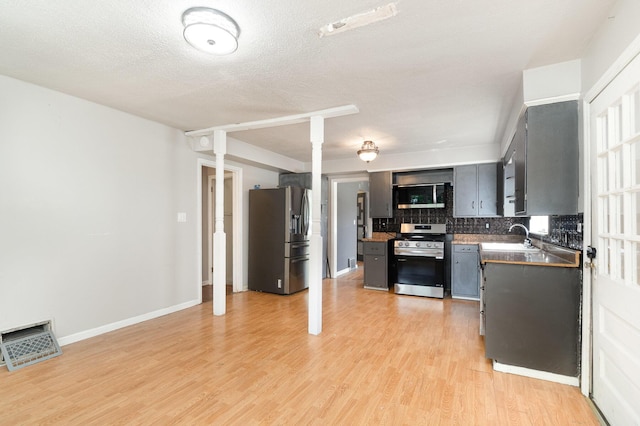 2958 E Stewart Rd, Midland, MI 48640 - kitchen with stainless steel appliances, a sink, tasteful backsplash, light wood-type flooring, and ornate columns