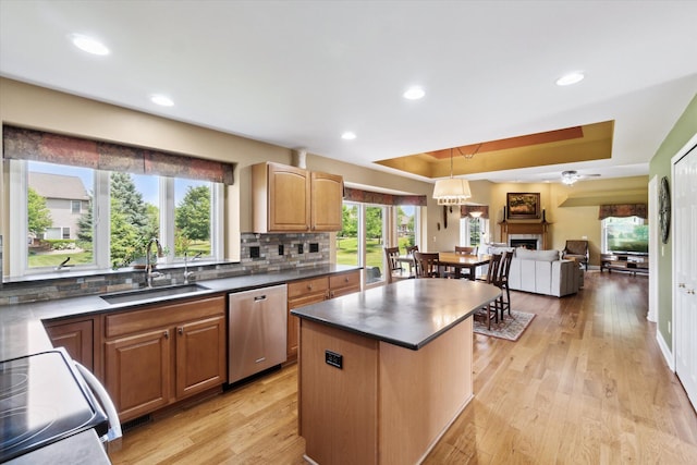 2056 Merlot Ct, Ann Arbor, MI 48108 - kitchen featuring stainless steel dishwasher, a sink, a raised ceiling, tasteful backsplash, and dark countertops