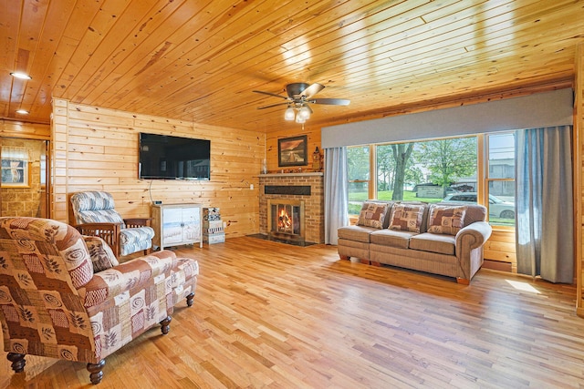 1018 Ruddiman Dr, North Muskegon, MI 49445 - living room featuring wood ceiling, ceiling fan, light wood-style flooring, a brick fireplace, and wood walls
