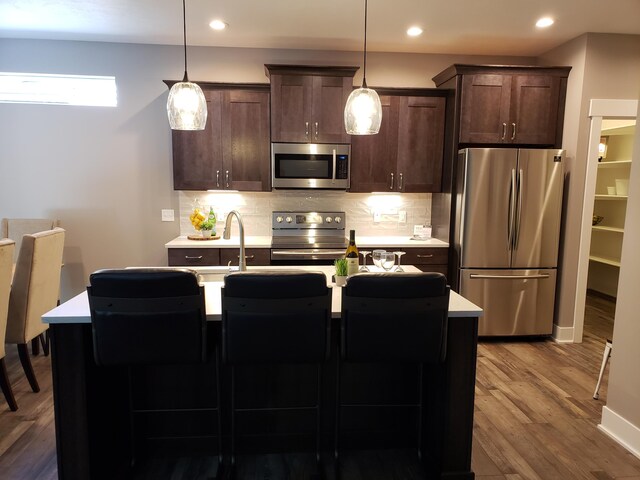 9421 Sassafras Trl Unit 76, Portage, MI 49002 - kitchen with stainless steel appliances, light countertops, tasteful backsplash, wood finished floors, and dark brown cabinetry