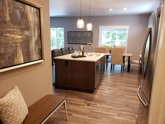 9421 Sassafras Trl Unit 76, Portage, MI 49002 - kitchen featuring appliances with stainless steel finishes, dark brown cabinets, light wood-style flooring, light countertops, and healthy amount of natural light