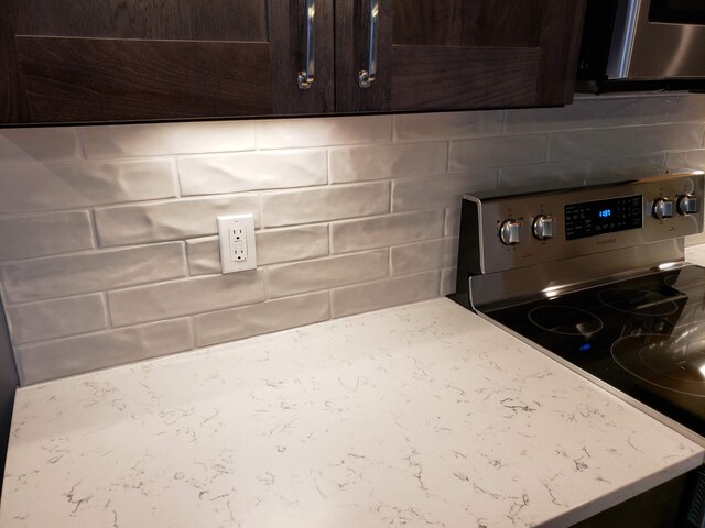 9421 Sassafras Trl Unit 76, Portage, MI 49002 - kitchen view of stainless steel appliances, dark brown cabinetry, tasteful backsplash, and light stone counters