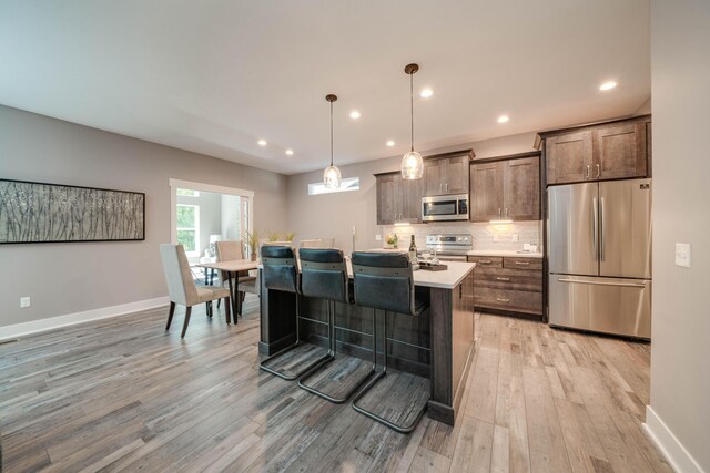 9421 Sassafras Trl Unit 76, Portage, MI 49002 - kitchen with stainless steel appliances, light wood-style flooring, light countertops, an island with sink, and tasteful backsplash