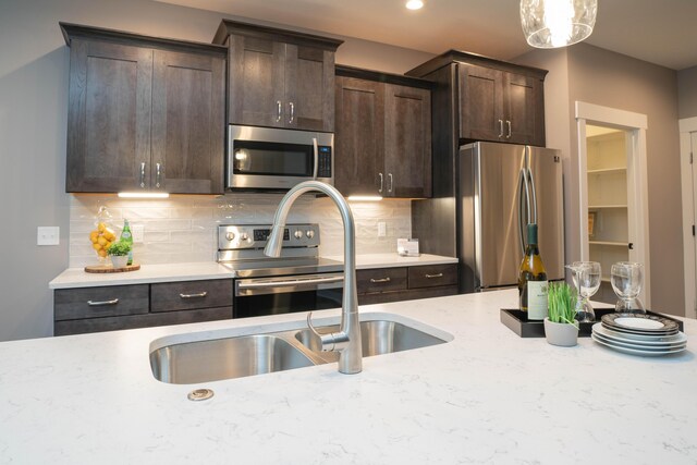 9421 Sassafras Trl Unit 76, Portage, MI 49002 - kitchen with appliances with stainless steel finishes, dark brown cabinets, decorative backsplash, light stone counters, and recessed lighting