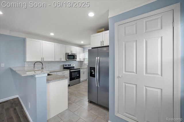 233 W 11 Mile Rd, Madison Heights, MI 48071 - kitchen with appliances with stainless steel finishes, tasteful backsplash, a peninsula, white cabinets, and light stone counters