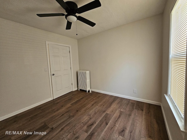 1902 Newberry St, Saginaw, MI 48602 - empty room featuring radiator heating unit, dark wood-type flooring, baseboards, and ceiling fan