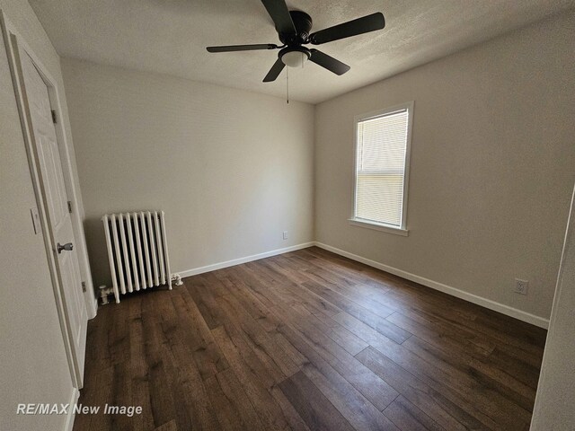 1902 Newberry St, Saginaw, MI 48602 - empty room featuring radiator, dark wood finished floors, a ceiling fan, and baseboards